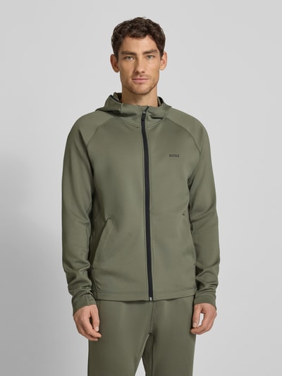 Männermodel trägt Regular Fit Trainingsjacke aus schnell trocknendem Gewebe Modell 'SICON ACTIVE' von BOSS Green, Optik: Unifarben, mit Kapuze, Reißverschluss, Label-Print, Reißverschlusstaschen, Daumenschlaufen und Langarm, Ganzkörperansicht von vorne.