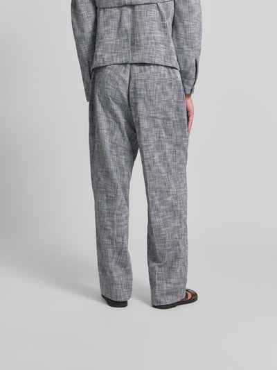Männermodel trägt Wide Fit Stoffhose mit Bügelfalten von Officine Générale, Reine Baumwolle, Gesäßtasche, elastischer Bund, Ganzkörperansicht Rückansicht.