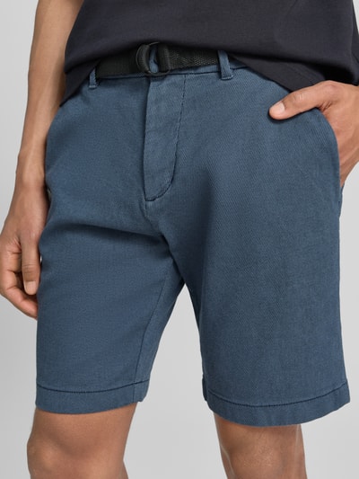 Männermodel trägt Regular Fit Chinoshorts aus Baumwoll-Mix von Tom Tailor Denim in Bi-Color Optik mit Gürtel, Knopf, seitlichen Eingrifftaschen und Gesäßtasche, Nahaufnahme Oberkörper.
