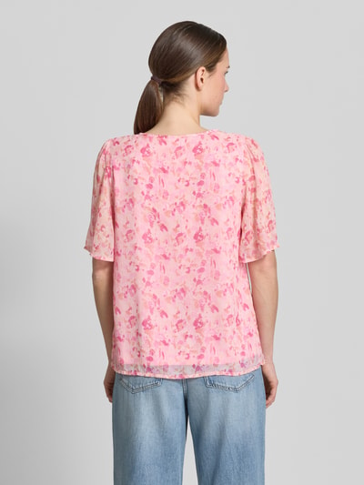Vrouwenmodel draagt Blusenshirt met druppelvormige hals model 'EMMA' van Vila in all-over look, regular fit, ruglengte maat 36: 60 cm, mouwlengte maat 36: 29 cm, lichte roze tinten met bloemenmotief, semi-transparante textuur, rugaanzicht, opname van hele lichaam.