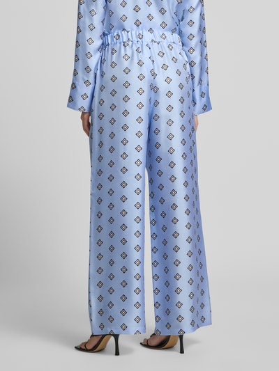 Vrouwenmodel draagt Seidenhose aus reiner Seide Modell 'LADATTI' van MM by Max Mara, satijn, lichtblauw met grafisch patroon, losse fit, elastische tailleband, Ganzkörperaanzicht achteraan.