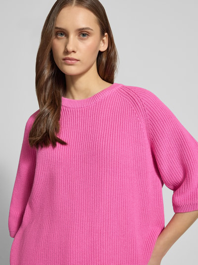 Frauenmodel trägt Oversized Strickpullover aus reiner Baumwolle Modell 'MARGE' von JJXX, Rundhalsausschnitt, 3/4-Arm, Strick-Optik, gerippte Abschlüsse, leuchtendes Pink, Nahaufnahme Oberkörper.