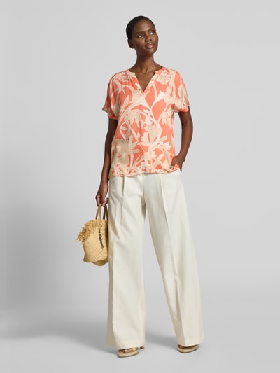Frauenmodel trägt Blusenshirt aus Viskose im Allover-Look von Milano Italy in Orange-Beige mit V-Ausschnitt, Regular-Fit, Ganzkörperansicht von vorne. Rückenlänge bei Größe 36: 59 cm, Ärmellänge bei Größe 36: 4 cm.