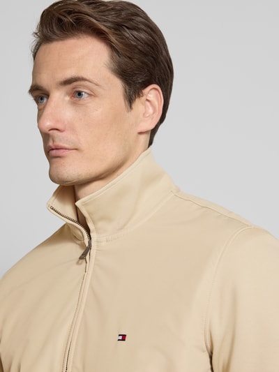 Männermodel trägt Regular Fit Blouson aus Baumwoll-Mix von Tommy Hilfiger in Beige, Stehkragen, Logo-Stitching, Nahaufnahme Oberkörper