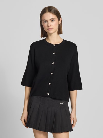 Modelka nosi Regular Fit Strickjacke aus Viskose-MIx Modell 'MAISIE' od Only, czarna, jednokolorowa, półdługie rękawy, okrągły dekolt, z ozdobnymi guzikami, drobny splot, krój regular fit, przód, zdjęcie całopostaciowe z przodu.