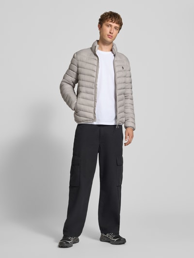Männermodel trägt Regular Fit Steppjacke mit Logo-Stickerei von REVIEW in Stepp-Optik, Grau, Eingrifftaschen, Ganzkörperansicht von vorne.