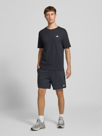Männermodel trägt Sweatshorts aus Baumwoll-Mix Modell 'FRENCH' von New Balance in Dunkelgrau, gerade Passform, Ganzkörperansicht von vorne.