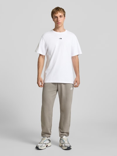 Männermodel trägt T-Shirt mit Logo-Stitching von The North Face aus reiner Baumwolle in Weiß, gerader Schnitt, Ganzkörperansicht von vorne.