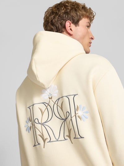Männermodel trägt Relaxed Fit Hoodie mit Känguru-Tasche von REVIEW in Creme mit floraler Stickerei, Nahaufnahme Rückansicht. Baumwoll-Mix, elastische Abschlüsse.
