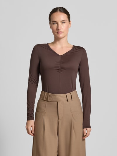Frauenmodel trägt Langarmshirt mit abgerundetem Rumpfabschluss von MARC CAIN in Braun, körpernaher Schnitt, V-Ausschnitt, Ganzkörperansicht von vorne.