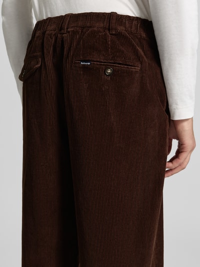 Männermodel trägt Relaxed Fit Cordhose aus Baumwoll-Mix von Barbour in Dunkelbraun mit feiner Rippenstruktur, Nahaufnahme Rückansicht.