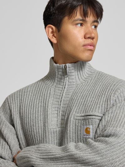 Männermodel trägt Troyer mit Brustleistentasche Modell 'DETROIT' von Carhartt Work In Progress, grob gestrickt, graue Farbe, Nahaufnahme Oberkörper.