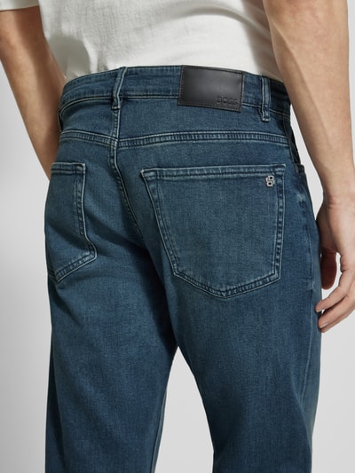 Männermodel trägt Straight Fit Jeans aus Baumwoll-Mix Modell 'RE.MAINE BO CHANGE' von BOSS Orange, Denimoptik, Ganzkörperansicht Rückansicht.
