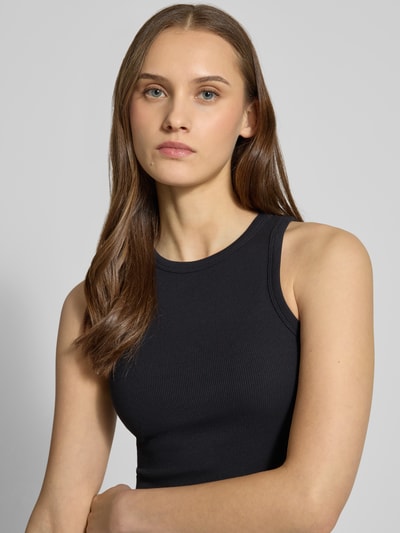 Frauenmodel trägt Tanktop in Ripp-Optik von REVIEW, Baumwoll-Elasthan-Mix, eng anliegende Passform, Rundhalsausschnitt, Nahaufnahme Oberkörper.