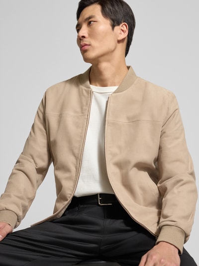 Männermodel trägt Bomberjacke aus Ziegenleder von Profuomo in Beige, gerader Schnitt, Stehkragen, Eingrifftaschen, Nahaufnahme Oberkörper.