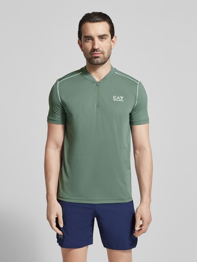 Männermodel trägt Regular Fit T-Shirt mit Stehkragen von EA7 Emporio Armani in Grün mit Reißverschluss und Label-Print, Ganzkörperansicht von vorne. Rückenlänge bei Größe M: 70 cm.