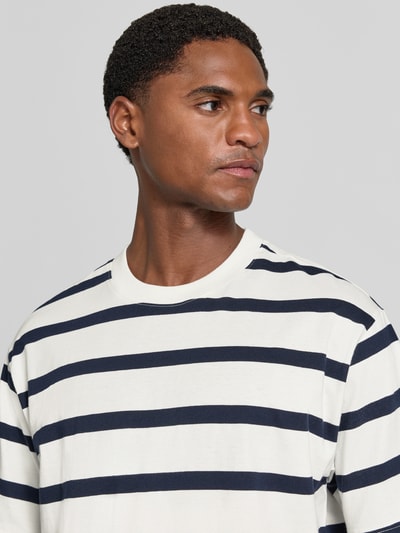Männermodel trägt T-Shirt mit geripptem Rundhalsausschnitt von MCNEAL in Weiß mit dunkelblauen Streifen, Nahaufnahme Oberkörper, Regular Fit, Rückenlänge bei Größe L 74 cm.