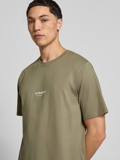 Męskimodel nosi T-Shirt mit Logo und Rundhalsausschnitt von Jack & Jones, zielony, bawełna ekologiczna, krój regular fit, okrągły dekolt, logo, długość tyłu w rozmiarze M: 68 cm, zbliżenie na górną część ciała