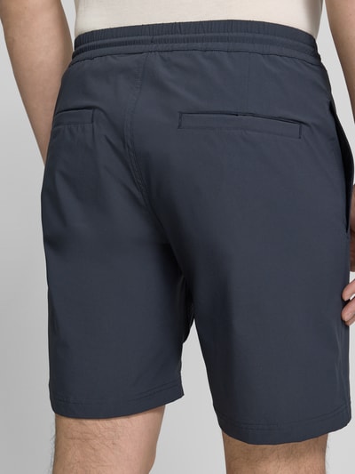 Männermodel trägt Straight Fit Shorts mit Eingrifftaschen Modell 'Drift' von SCANDINAVIAN EDITION, elastischer Material-Mix, Ganzkörperansicht Rückansicht.
