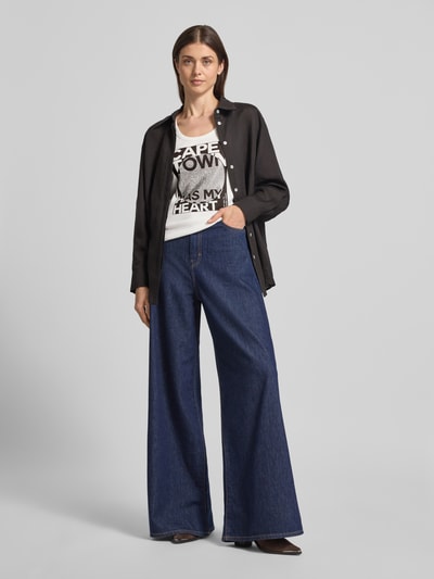 Frauenmodel trägt Slim Fit Top mit Strasssteinbesatz Modell 'Cape Town' von monari, weiß mit Statement-Print, elastischer Baumwoll-Mix, Ganzkörperansicht von vorne.