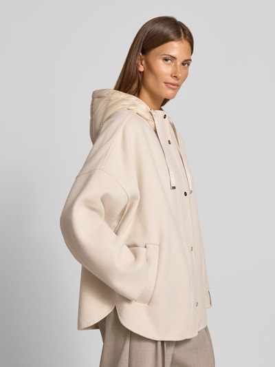 Frauenmodel trägt Jacke mit Kapuze von COMMA in Beige mit lockerer Passform, seitlichen Eingrifftaschen und Knopfleiste, Ganzkörperansicht von vorne.