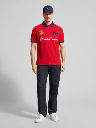 Männermodel trägt Regular Fit Poloshirt aus reiner Baumwolle von Polo Ralph Lauren in Rot mit Logo-Stitching und Piqué-Struktur, Ganzkörperansicht von vorne.