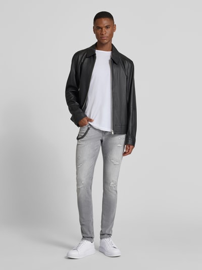 Männermodel trägt Tapered Fit Jeans mit Ketten-Detail von Antony Morato im Destroyed-Look, hellgrau, mit 5-Pocket-Design, Ganzkörperansicht von vorne.