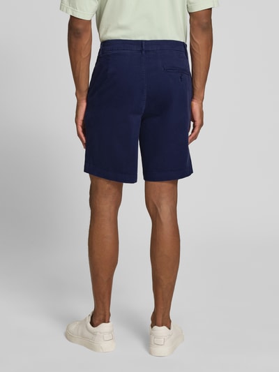 Männermodel trägt Regular Fit Chinoshorts aus Baumwoll-Mix Modell 'CHINO' von Armedangels in Dunkelblau, Gesäßtasche, Ganzkörperansicht Rückansicht