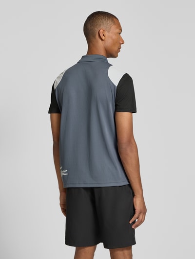 Männermodel trägt Regular Fit Sport-T-Shirt im Colorblock-Design von Lacoste, dunkle und weiße Farbtöne, glatte Struktur, Ganzkörperansicht Rückansicht, Herren Sport-T-Shirt von Lacoste Sport.