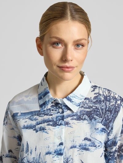 Vrouwenmodel draagt slim fit blouse in blauw-witte all-over look van puur katoen, Slim Fit, model 'Hamptons Landschaft' van monari, maat 36, maat 36: ruglengte 63 cm, mouwlengte 64 cm, detailopname bovenlichaam.