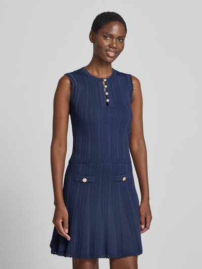 Frauenmodel trägt Stricktop in Pointelle-Strick mit kurzer Knopfleiste von GUESS, Viskose-Mix, dunkelblau, körpernah geschnitten, Nahaufnahme Oberkörper.