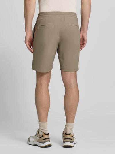 Männermodel trägt Straight Fit Shorts mit Eingrifftaschen Modell 'Drift' von SCANDINAVIAN EDITION in Beige, elastischer Bund, Ganzkörperansicht Rückansicht