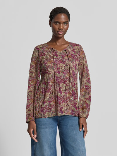 Frauenmodel trägt Relaxed Fit Bluse mit Allover-Paisley-Print Modell 'Leonora' von ZABAIONE, bunte Farben, Zierschleife, Jeans, Ganzkörperansicht von vorne.