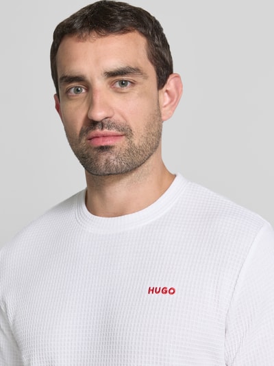 Męski model nosi Męski t-shirt z mieszanki bawełny model 'AUSTIN' od HUGO w białym kolorze, struktura wafel, bliska perspektywa górnej części tułowia.