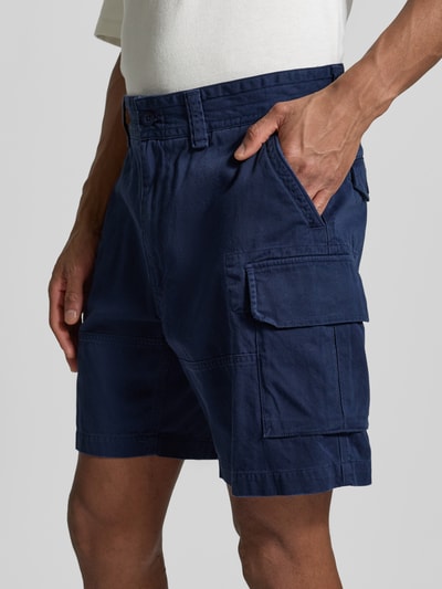 Męski model nosi Szorty cargo Relaxed Fit z czystej bawełny od Polo Ralph Lauren, jednokolorowe, wyhaftowane logo, szlufki na pasek, zapięcie na guzik i kryty zamek błyskawiczny, wpuszczane kieszenie boczne, kieszenie z tyłu z guzikami, kieszenie cargo, tkana faktura, widok całego ciała z przodu.