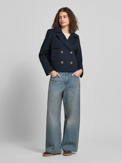 Vrouwenmodel draagt Regular Fit Trenchcoat mit Umlegekragen van Review in donkerblauw, zuiver katoen, regular fit, tweerijige knoopsluiting, steekzakken, ruglengte bij maat S 55 cm, schouderbreedte 45 cm, borstwijdte 53 cm, mouwlengte 62 cm, geheellichaamszicht van voren.