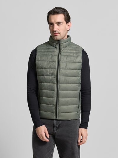 Männermodel trägt Regular Fit Steppweste mit Stehkragen Modell 'ODENO2' von BOSS Orange in Unifarben, Ganzkörperansicht von vorne.