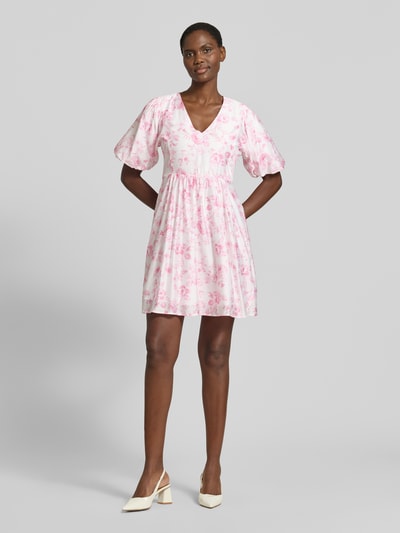 Frauenmodel trägt Tailliertes Freizeitkleid aus Viskose-Mix Modell 'BLISS' von Vero Moda, Optik: Allover-Muster, Mini-Länge, V-Ausschnitt, Ballonärmel, feine Webstruktur, Ganzkörperansicht von vorne.