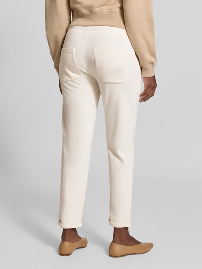 Vrouwenmodel draagt sweatpants uit katoenmix van Juvia in crème met steekzakken, elastische band en fleece binnenkant, nauwsluitende pasvorm, bandwijdte maat S 84 cm, binnenbeenlengte 68 cm, detailopname rugaanzicht.
