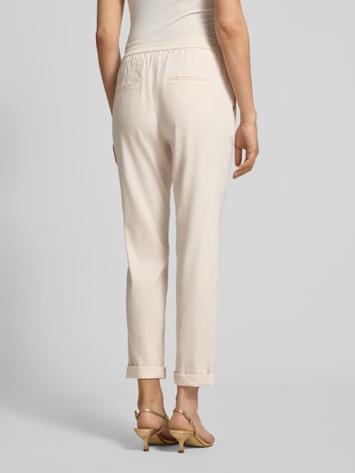 Frauenmodel trägt Straight Fit Leinenhose mit Viskose-Anteil von Marc Cain in Beige mit Gesäßtaschen, elastischer Bund, Ganzkörperansicht Rückansicht.
