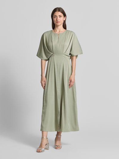 Vrouwenmodel draagt Midikleid mit V-Ausschnitt Modell 'VIANNA' van Copenhagen Muse in lichtgroen met draperingen, getailleerde fit, V-hals, materialen met gladde textuur, volledige lichaamsaanzicht van voren