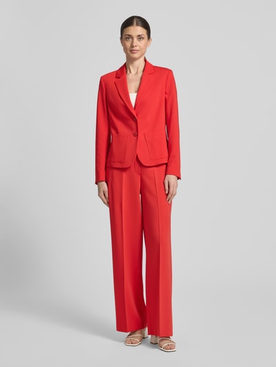 Modelka kobieca ma na sobie Slim Fit Blazer mit Reverskragen od More & More, mieszanka materiałów z dodatkiem wiskozy, krój slim fit, kołnierz z połami, listwa guzikowa, nakładane kieszenie, długość tyłu w rozmiarze 36: 55 cm, szerokość w rozmiarze 36: 40 cm, długość rękawów w rozmiarze 36: 61 cm, intensywnie czerwony kolor, gładka faktura, całkowity widok z przodu.
