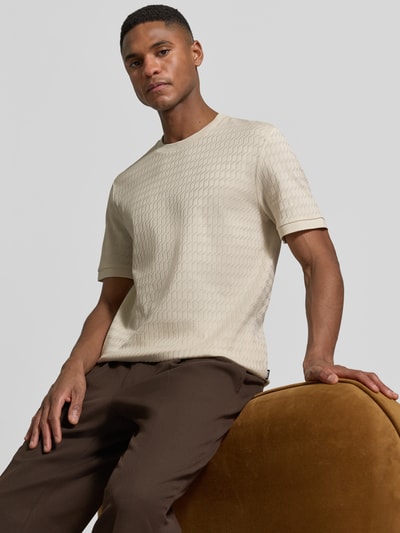 Männermodel trägt Regular Fit T-Shirt aus reiner Baumwolle Modell 'THOMSON' von BOSS in Creme mit feinem Strukturmuster, Nahaufnahme Oberkörper.