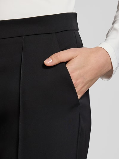 Frauenmodel trägt schwarze Culotte mit Längsnähten Modell 'PALINA' von Raffaello Rossi, glatte Textur, Nahaufnahme Oberkörper, Produktdetails sichtbar.