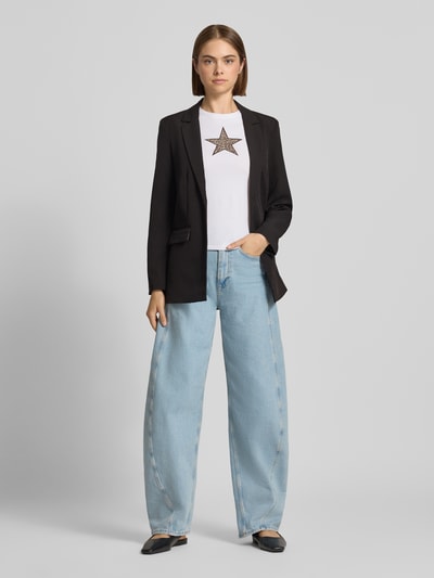 Frauenmodel trägt einen schwarzen Regular Fit Longblazer mit Leo-Innenmuster Modell 'BOZZY' von PIECES, helle Jeans, Ganzkörperansicht von vorne.
