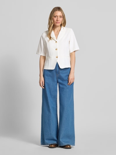 Frauenmodel trägt Blazer mit Viskose-Anteil Modell 'Kate' von ICHI in Offwhite, Elastischer-Material-Mix, Tailliert, Reverskragen, Halbarm, durchgängige Knopfleiste, Paspeltaschen, weiche Textur, kombiniert mit blauer, weiter Jeans, Ganzkörperansicht von vorne.