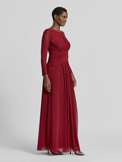 Modelka kobieca nosi wieczorową suknię 'Abendkleid mit tiefem Rückenausschnitt und Raffungen' od TROYDEN COLLECTION, bordowy szyfon, krój taliowany, okrągły dekolt, wycięcie w kształcie łezki, rękawy półprzezroczyste, marszczenia, głęboko wycięty tył, zamek z tyłu, długość tyłu w rozmiarze 36: 152 cm, szerokość w rozmiarze 36: 36 cm, długość rękawa w rozmiarze 36: 58 cm, pełny widok przodu.