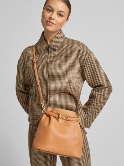 Frauenmodel trägt Bucket Bag aus echtem Rindsleder von Lauren Ralph Lauren in Hellbraun, offene Form mit Zierschnalle und abnehmbarem Schulterriemen, Innenfach mit Reißverschluss, Maße 24x24x14 cm, Schulterriemen 117 cm, Ganzkörperansicht von vorne.