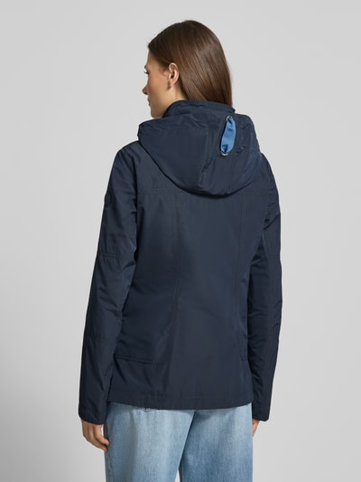 Vrouwenmodel draagt Weather Protection Jack met ritssluitzakken van Gil Bret in regular fit, donkerblauw met kap, ruglengte 66 cm, schouderbreedte 40 cm, borstwijdte 48 cm, mouwlengte 63 cm, rugaanzicht op volledige lichaamslengte.