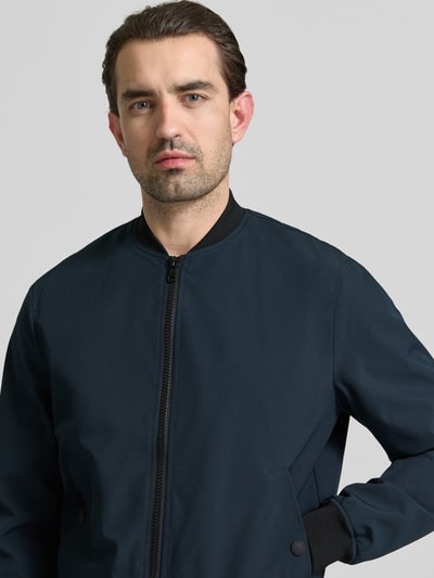 Männermodel trägt Regular Fit Bomberjacke mit Stehkragen von MCNEAL, dunkelblau, elastischer Material-Mix, Nahaufnahme Oberkörper.